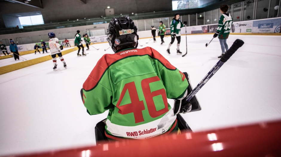 Goalie von hinten, der vor einem Eishockeyfeld steht